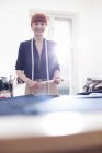 Portrait femme confiant tailleur tenant des ciseaux dans l'atelier de vêtements pour hommes — Photo de stock