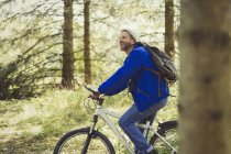 Hombre sonriente montando en bicicleta de montaña en los bosques - foto de stock