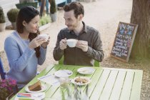 Couple enjoying cappuccinos and dessert an outdoor cafe — Stock Photo