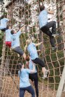 Gente escalando red en campo de entrenamiento carrera de obstáculos - foto de stock