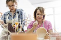 Mature women painting pottery in studio — Stock Photo