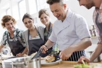 Students watching chef teacher in cooking class kitchen — Stock Photo