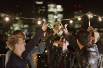 Jovens homens tostando garrafas de cerveja na festa no telhado — Fotografia de Stock
