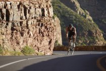 Hombre triatleta ciclismo cuesta arriba - foto de stock
