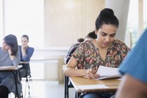 Ernsthafte weibliche College-Studentin macht Test am Schreibtisch im Klassenzimmer — Stockfoto