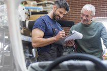 Mechaniker mit Klemmbrett arbeiten in Autowerkstatt — Stockfoto