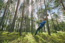 Läufer streckt sich mit Widerstandsband an Baum im Wald — Stockfoto