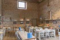 Tables in vacant restaurant with brick walls and vaulted ceiling — Stock Photo