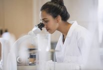 Científica femenina que utiliza microscopio en laboratorio - foto de stock