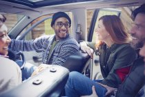 Smiling friends talking and riding in car — Stock Photo