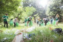 Environmentalist volunteers picking up trash in field — Stock Photo