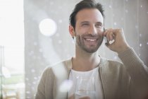 Усміхнений чоловік п'є воду і розмовляє по мобільному телефону — стокове фото