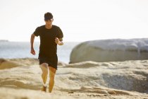 Триатлонист бегает по солнечной скалистой тропе — стоковое фото