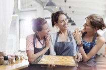 Smiling female friends enjoying cooking class in kitchen — Stock Photo