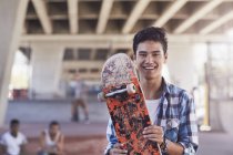 Портрет усміхненого хлопчика-підлітка, що тримає скейтборд у скейтборді — стокове фото