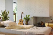 Gitarre lehnt am Kamin hinter Chaise im Wohnzimmer — Stockfoto