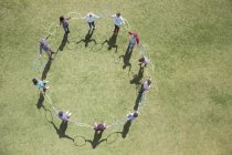 Team connected in circle by plastic hoops in sunny field — Stock Photo