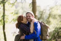 Retrato sonriente pareja besándose senderismo en el bosque - foto de stock