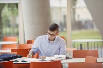 Estudiante universitario masculino estudiando en la mesa - foto de stock