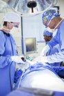 Cirurgiões que realizam cirurgia em centro cirúrgico na clínica médica — Fotografia de Stock