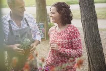 Gärtnerin hilft Frau mit Topfblumen — Stockfoto