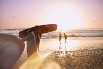 Человек с кайтбордом на пляже заката — стоковое фото