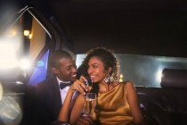 Celebrity couple drinking champagne inside limousine outside event — Stock Photo