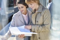 Geschäftsfrauen lesen Papierkram auf sonnigem Bahnsteig — Stockfoto