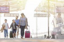 Família andando puxando malas no átrio do aeroporto — Fotografia de Stock