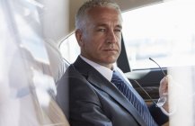 Pensive businessman riding in back seat of town car — Stock Photo