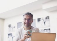 Усміхнений чоловік п'є каву в ноутбуці — стокове фото