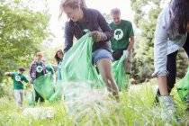 Environmentalist volunteers picking up trash in field — Stock Photo