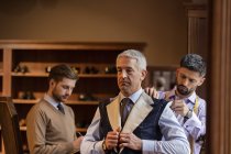 Tailors fitting businessman for suit in menswear shop — Stock Photo