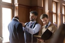 Tailors examining suit and taking notes in menswear shop — Stock Photo