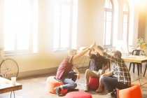 Творческие бизнесмены держатся за руки в солнечном офисе — стоковое фото