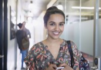Portrait confident college student with cell phone in corridor — Stock Photo