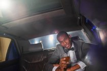 Portrait of confident celebrity drinking cocktail inside limousine outside event — Stock Photo
