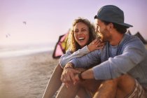 Пара сміється сидить на пляжі — стокове фото