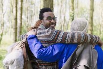 Porträt lächelnder Mann umarmt Freunde beim Wandern im Wald — Stockfoto