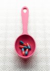 Medical capsules in pink spoon — Stock Photo