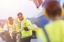 Airport ground crew workers with clipboard talking on tarmac — Stock Photo