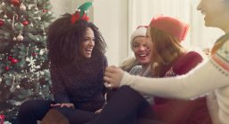 Friends talking and laughing near Christmas tree — Stock Photo