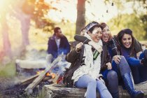 Friends laughing roasting marshmallows at campfire — Stock Photo