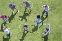People spinning in plastic hoops in sunny grass — Stock Photo