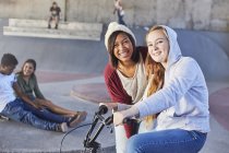 Portrait smiling teenage girls with BMX bicycle at skate park — Stock Photo