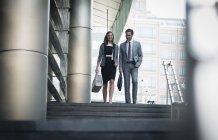 Корпоративный бизнесмен и деловая женщина спускаются по лестнице на улицу — стоковое фото