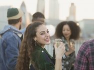 Portrait smiling young woman drinking champagne at rooftop party — Stock Photo