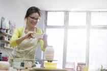 Donna matura fotografare vaso di ceramica con fotocamera telefono in studio — Foto stock