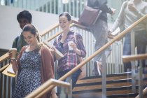 College students with coffee descending stairway — Stock Photo