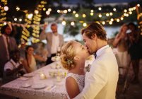 Pareja joven besándose durante la recepción de la boda en jardín doméstico - foto de stock